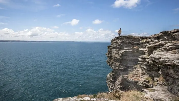 A person standing on the cliff tops overlooking the sea from Tintagel