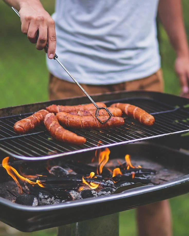 A camper grilling sausages