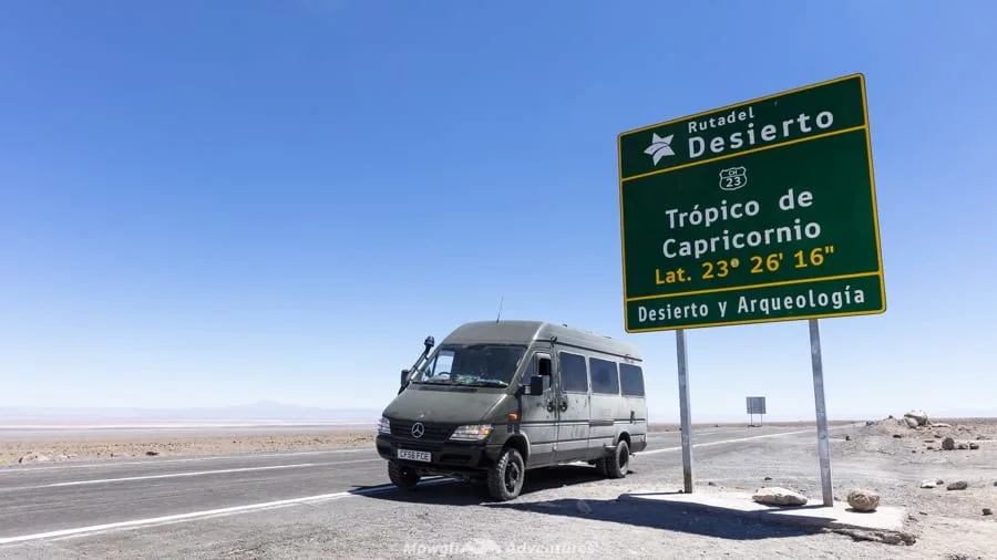 A Mercedes Sprinter campervan conversion beside the Tropic of Capricorn sign in Chile's Atacama desert