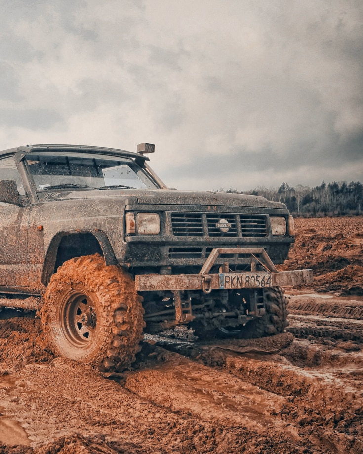 Overland vehicle with a snorkel fitted driving in thick, wet red mud