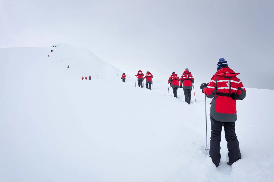 A team of people on expedition parks hiking in Antarctica