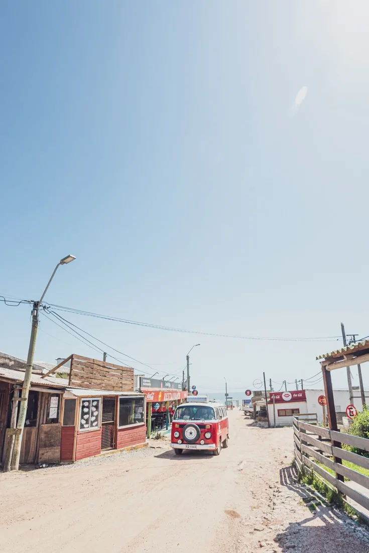 A red VW combi driving through the sandy roads of Punta del Diablo at the end of the summer season