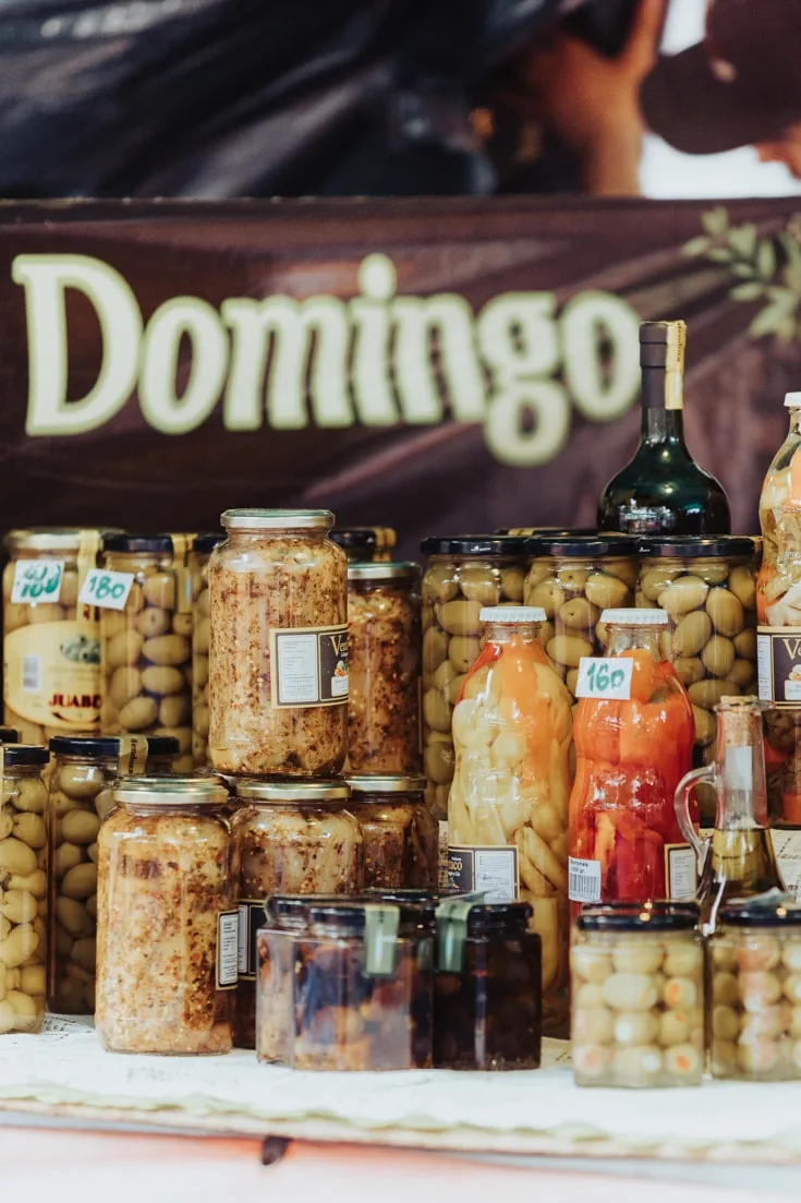 Artisanal jars of pickles for sale at Mataderos Market with a Domingo sign Sunday