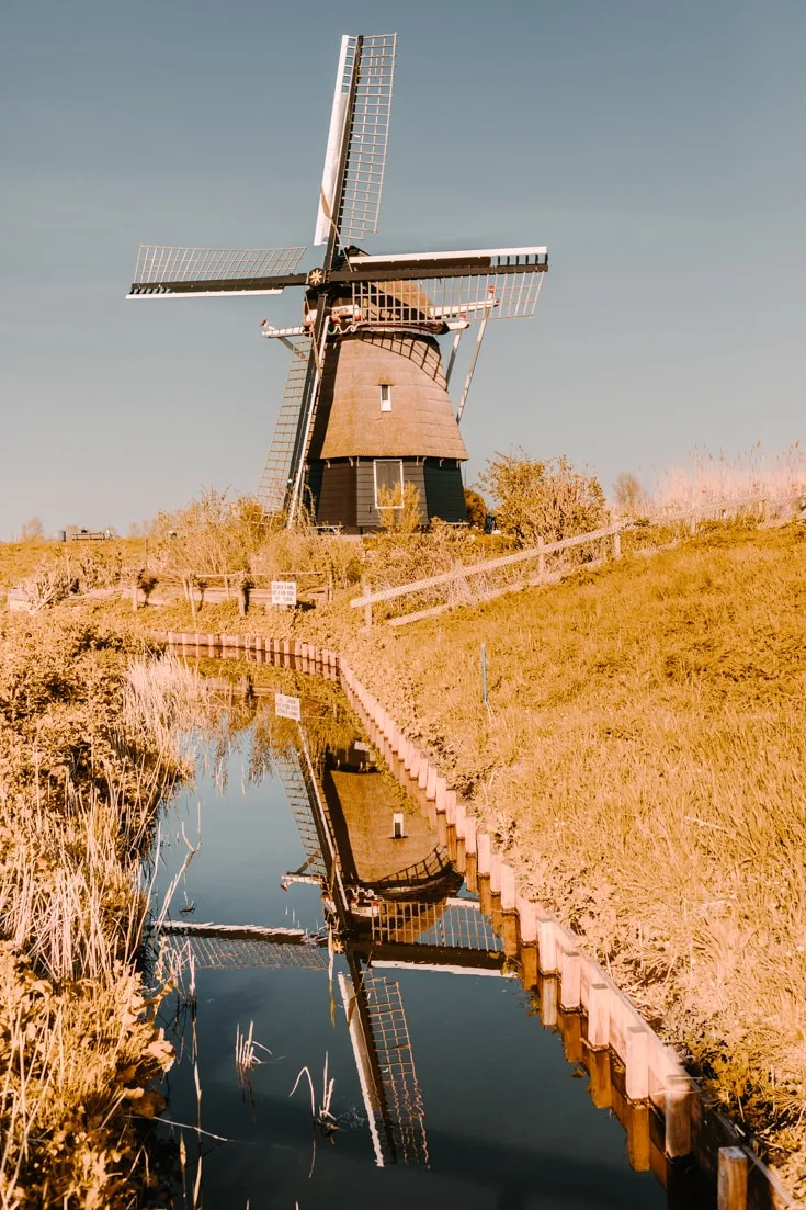 A lone windmill and its reflection in a canal in Haarlem Holland