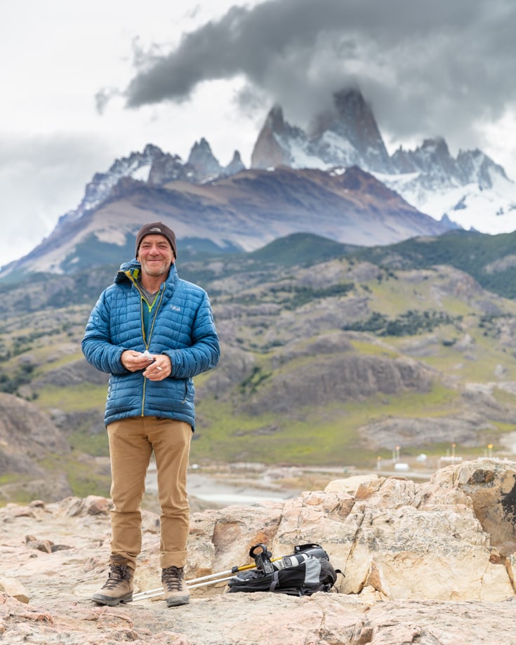 Standing at the top of a mountain in hiking gear opposite Mount Fitz Roy, Argentina 