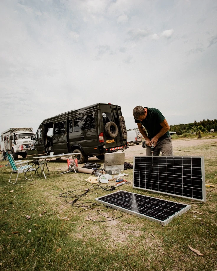 A man fitting solar panels to a Sprinter campervan conversion