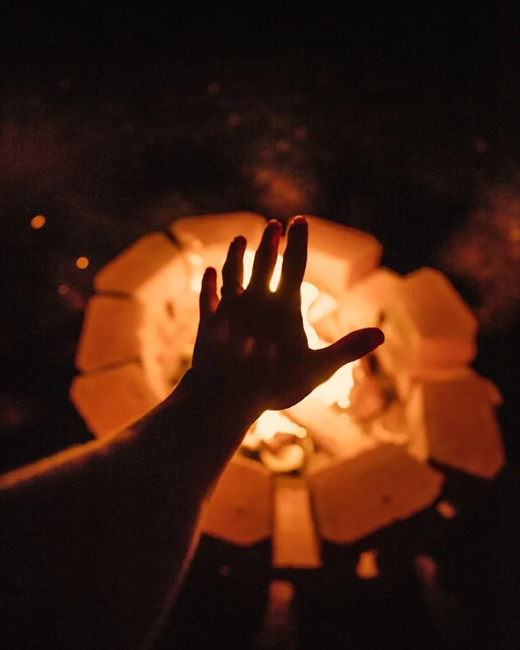 A hand warming itself over a fire