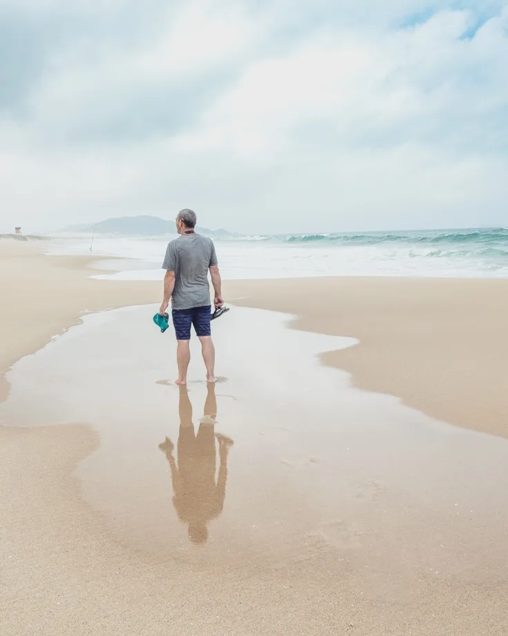 A man standing barefoot on a beach