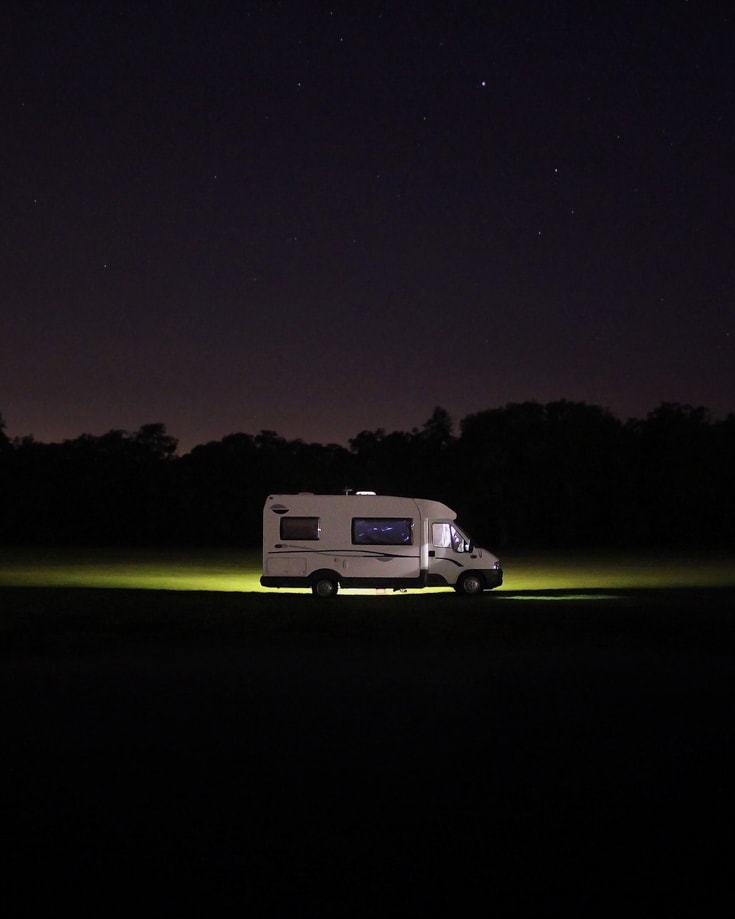 A campervan parked under a star filled night sky