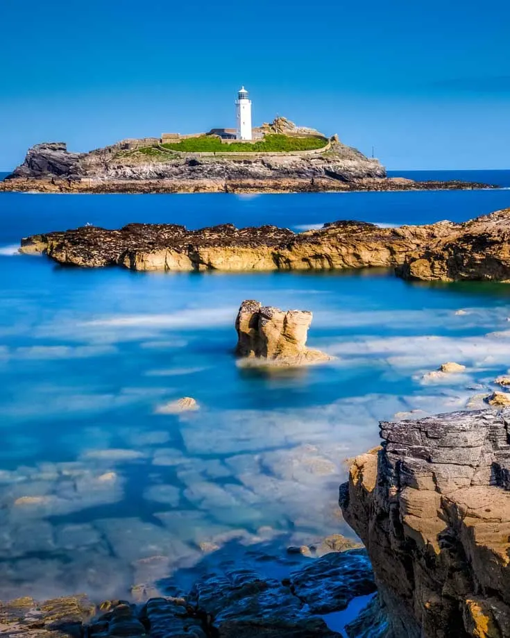 A clear day with blue skies and silky smooth sea at Godrevy lighthouse, St Ives