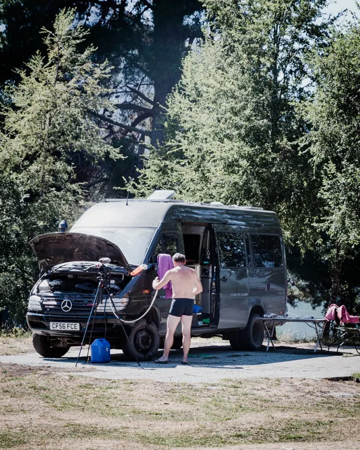 A man showering beside a campervan