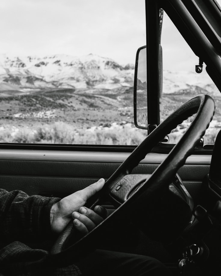 A black and white photo of a person test driving a campervan
