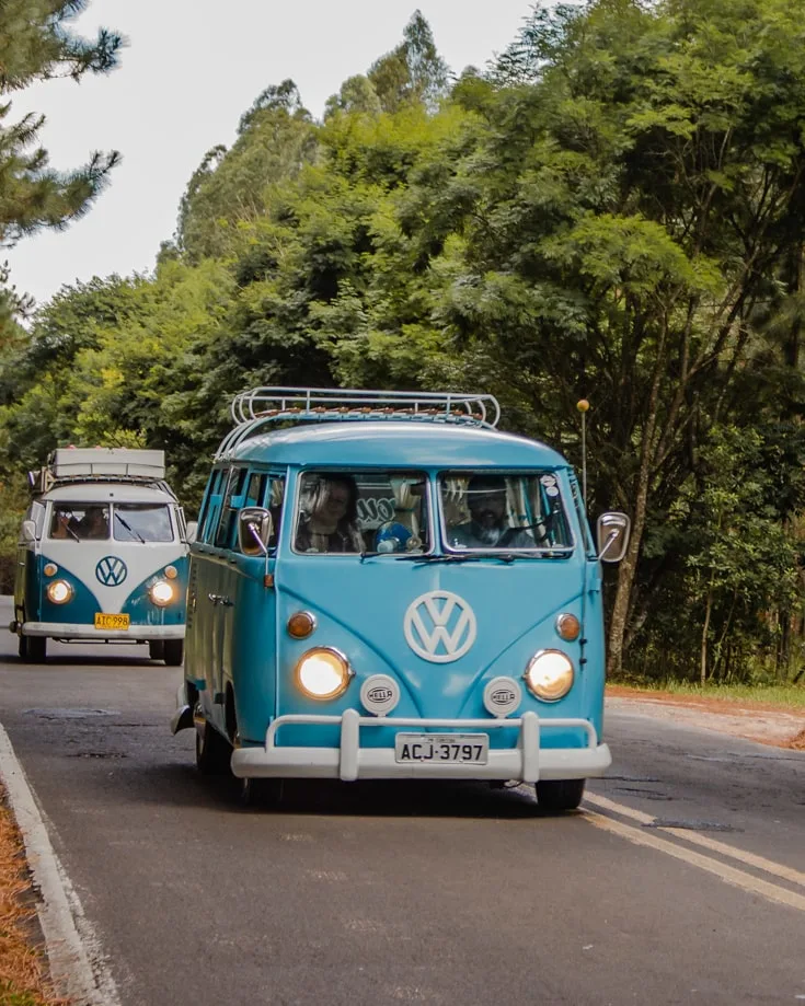2 retro VW campervans driving in convoy along a road