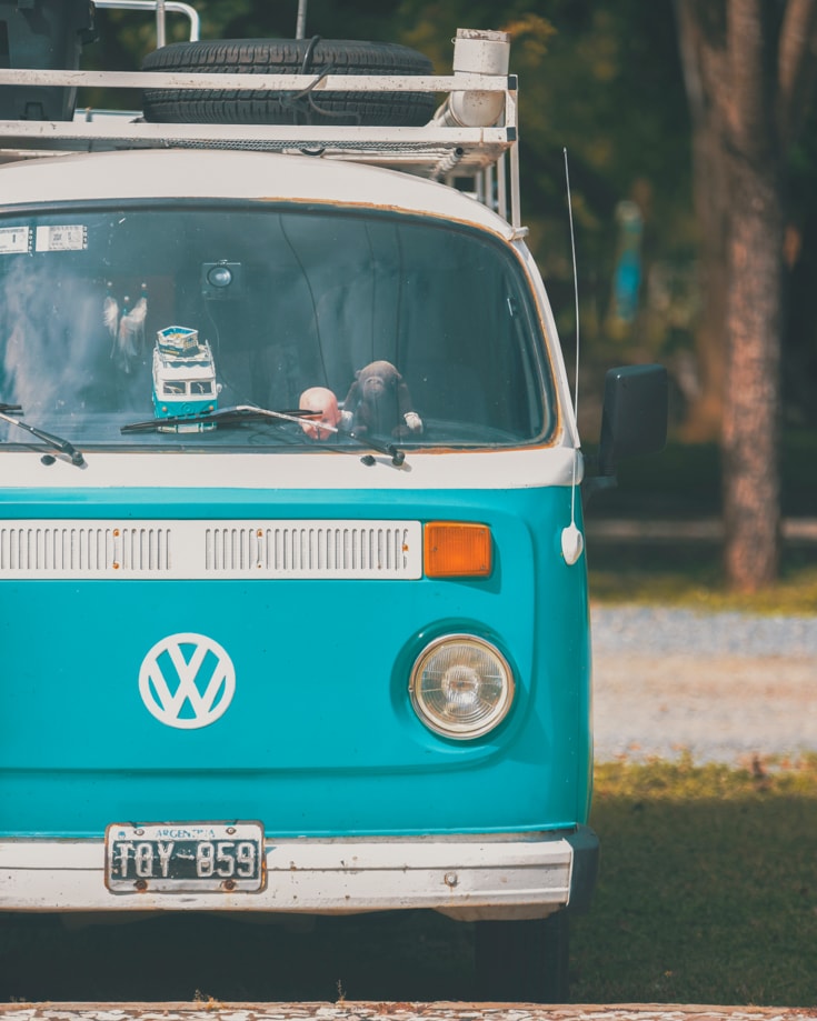 A close up of a blue and white VW campervan with a roof rack parked