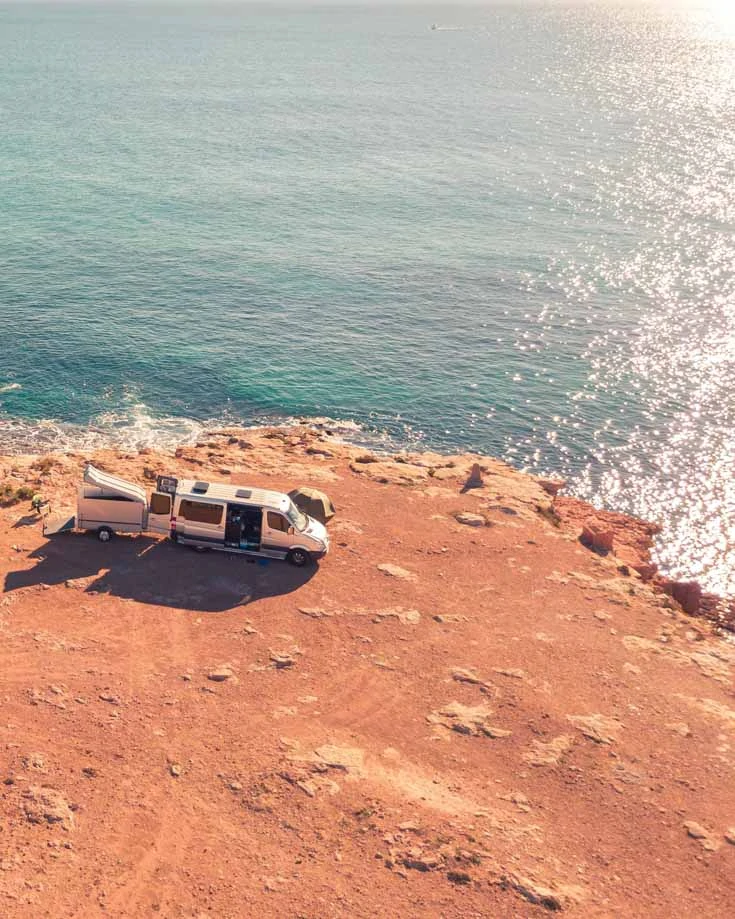 A camper with solar panels parked on a cliff edge on your next van life adventure