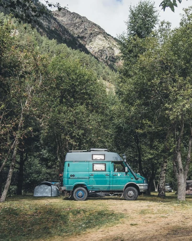 a campervan parked beneath trees