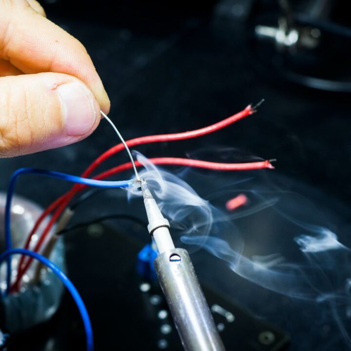 a close up of a hand holding a soldering iron