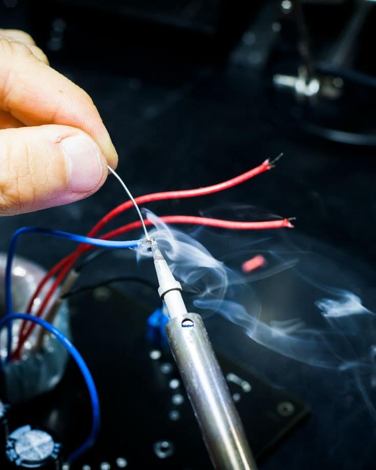 a close up of a hand holding a soldering iron