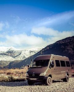 A Sprinter van conversion parked by a river in winter