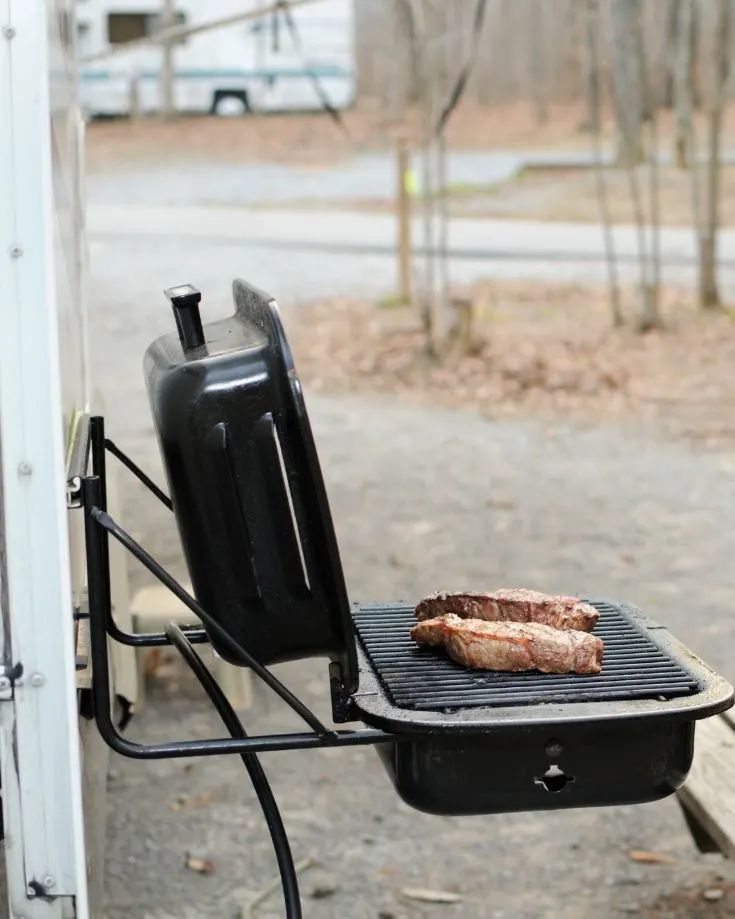a portable grill mounted on the side of an RV