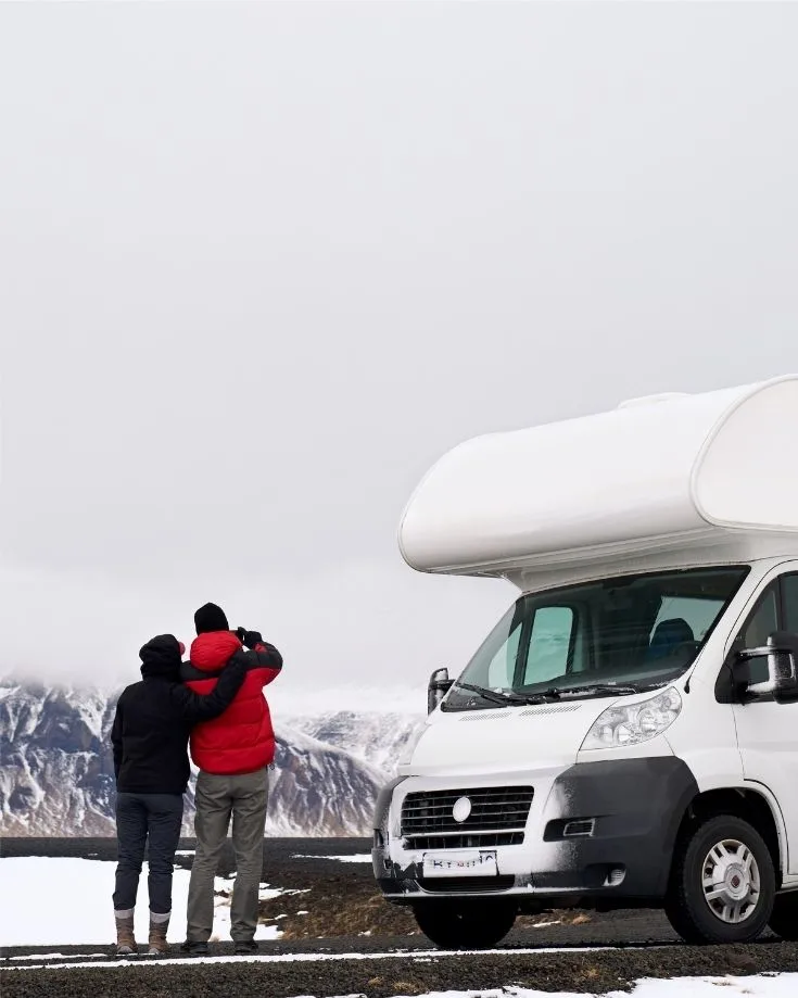Class C motorhome in a scenic mountain landscape with a couple of tourists