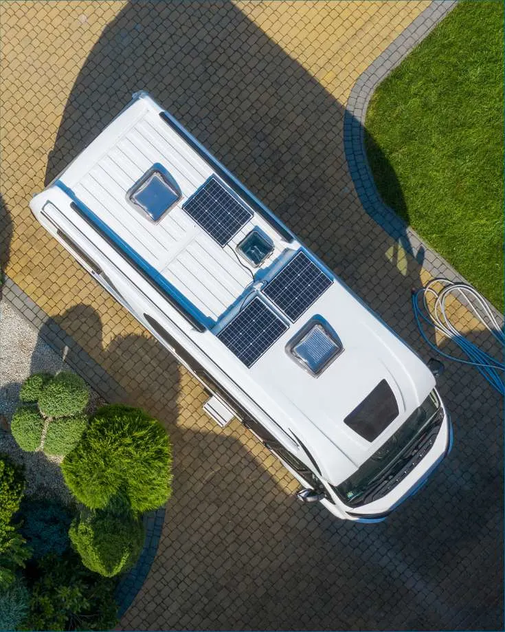 Aerial view of an RV parked in a scenic location, with soalr panels installed on the roof