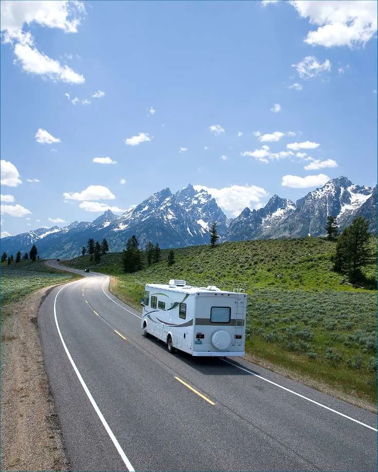 RV driving down road towards mountains
