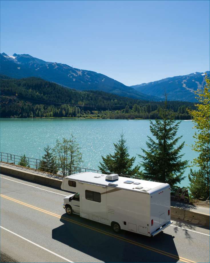 RV driving on road by lake in the mountains