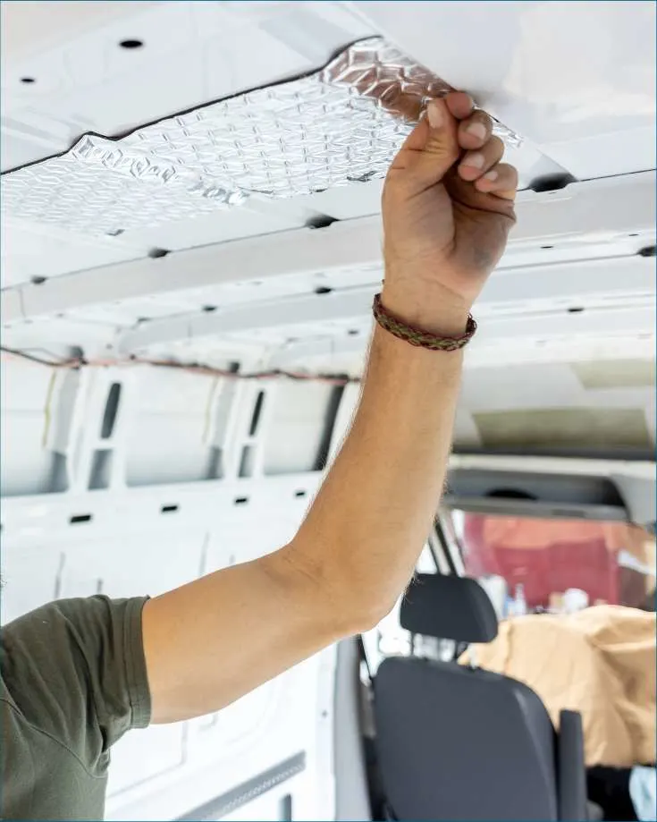 man applying sticky back insulation to a van