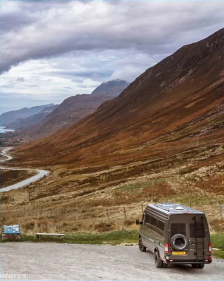 Van driving down a road with a view of a mountain valley