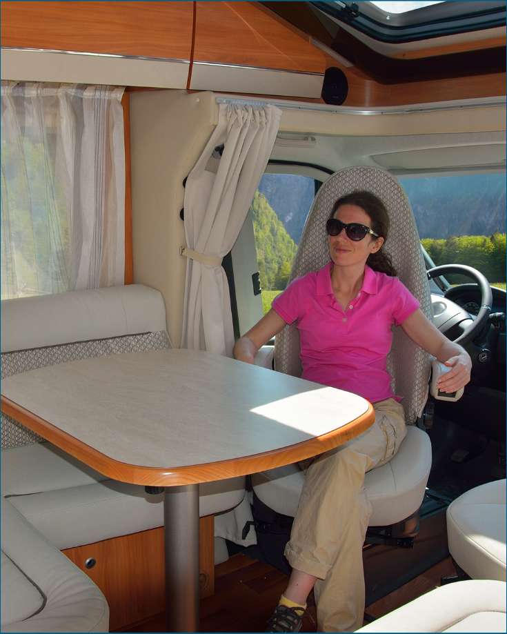 RVers relaxing inside their vehicle with a visible thermostat in the background, illustrating the ability to control the RV's climate for maximum comfort.